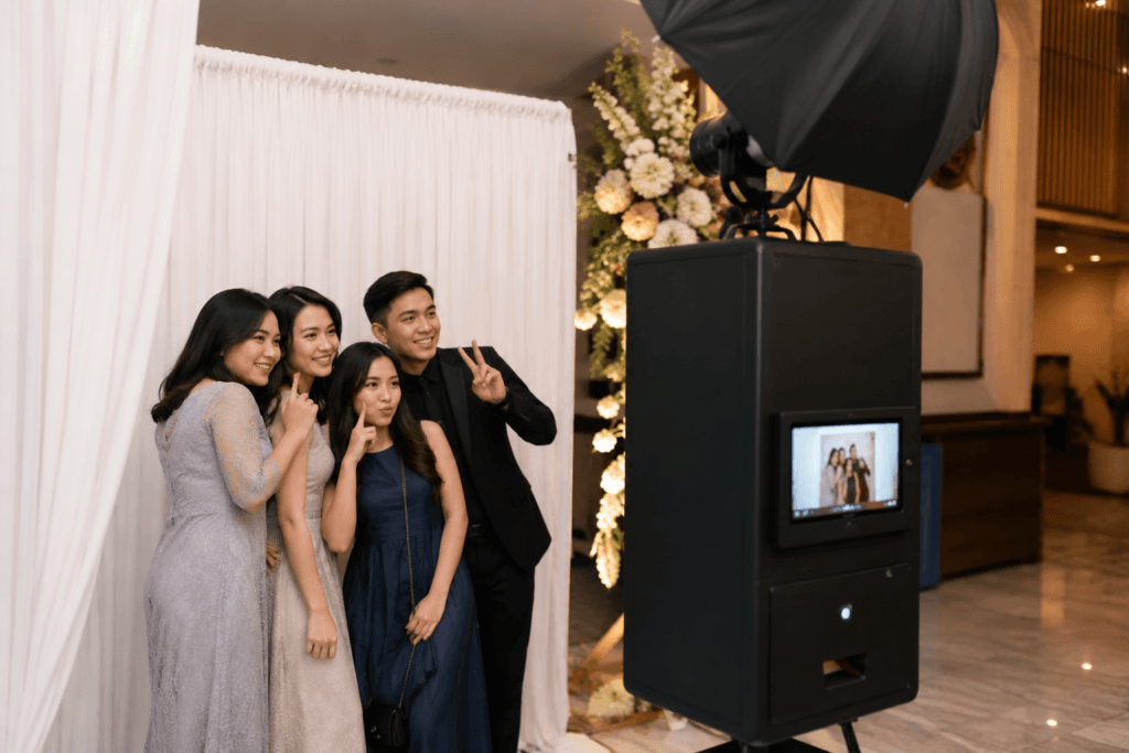 Empat tamu berpose ceria di depan instant print photobooth saat acara pernikahan